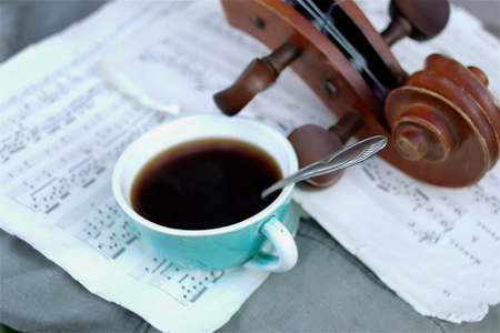 Cup of coffee on sheet music next to cello, closeup with particular focusの写真素材