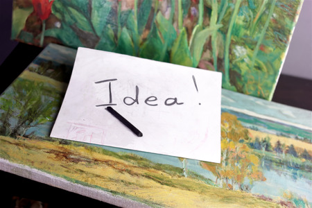 Hand written word Idea on a paper next to painting of landscape and flowersの写真素材