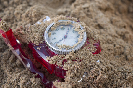 Closeup of the retro looking table clock buried in the sand, concept of disasterの写真素材