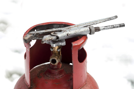 Red gas bottle and wrench on top of it, snow in he background.の写真素材