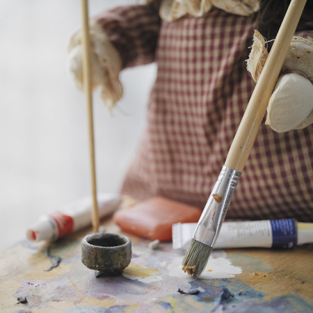 Closeup of a doll painting with artist brushes, selective focus indoor shotの写真素材