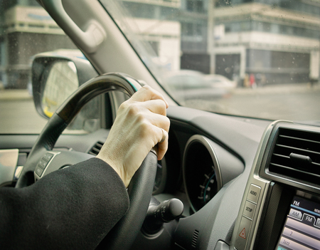 Driving a car and listen news or music, closeup of a male hand on a car wheel, filtered closeup shotの写真素材