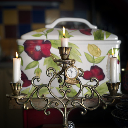 Retro looking clock hanging on a bronze candle holder, front closeup shot, concept of celebration or timeの写真素材