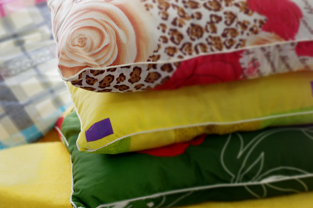 Pillows and pillowcases in various colors, stacked, cropped closeup with selective focusの写真素材