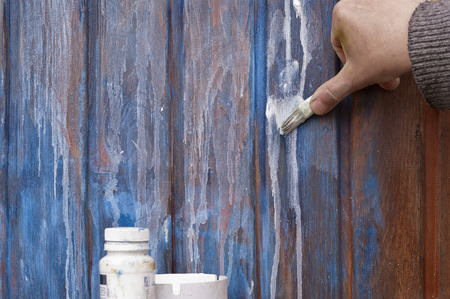 Male hand painting a wooden wall with a paintbrush, outdoor shot with no peopleの写真素材