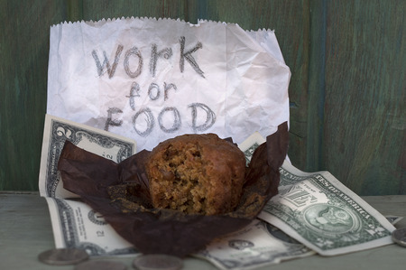 Bitten donut wrapped in paper and US dollars spread around next to a written message. Concept of employment issuesの写真素材