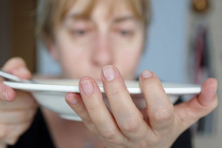 Woman holding gently a plate with hot food, selective focus indoor shotの写真素材