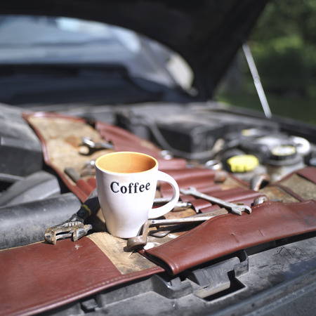 Open car hood, set of tools and coffee cup on top, fay time shot with selective focus and blurred backgroundの写真素材