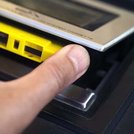 Male hand ejecting or loading music compact cassette, shallow depth of field macro shotの写真素材