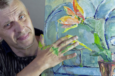 A matured artist working on his painting with dirty hands, studio cropped shotの写真素材