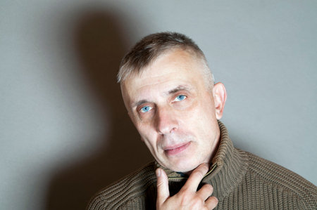 A man thinking, holding his head with hand and looking straight, horizontal studio shot
