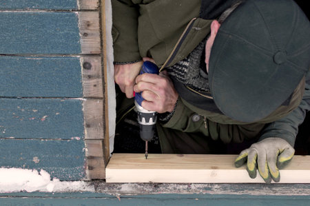 One worker drilling a plank while another assisting him. Outdoor filtered cropped shot の写真素材
