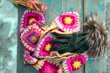 Woolen colorful scarf and leather gloves laid on the bench, overhead cropped shotの写真素材