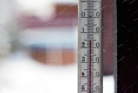 A temperature gauge closeup with flying snowflakes around, closeup with selective focus