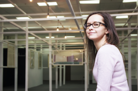 Female wearing glasses posing while visiting museum or exhibition, cropped filtered shotの写真素材