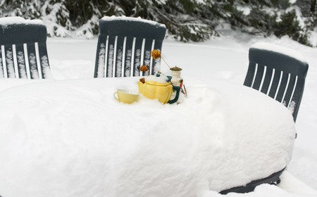 A dinner table with crockery and tea pot, covered with snow. Outdoor selective focus shotの写真素材
