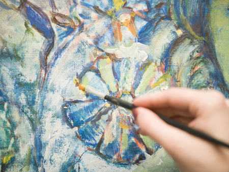 Artist hand painting a flower on the canvas, closeup shot with selective focusの写真素材