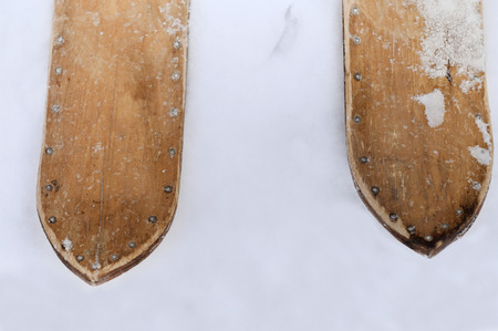 Overhead closeup of the hand made old wooden ski with visible nails standing on the snowの写真素材
