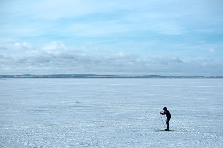 A silhouette of a skier running across the frozen lake, outdoor shotの写真素材