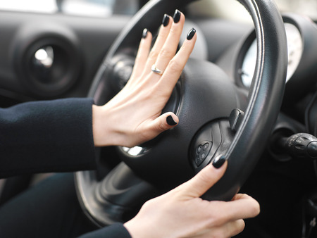 Manicured female fingers on a car horn, closeup with shallow depth of fieldの写真素材
