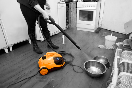 Woman cleaning floor with steam or hot water spray,  kitchen interior. Selective color shotの写真素材