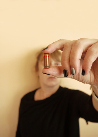 Woman holding a pistol ammo in her hand, focus in the foregroundの写真素材