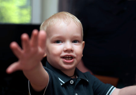 A little boy with blonde hair reaching hand asking for help or attention, selective focus photoの写真素材