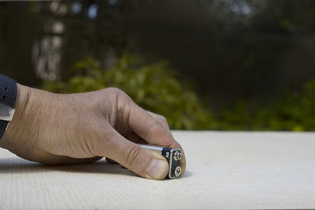 Male hand holding a 9 volt battery on a table top, outdoor cropped shotの写真素材