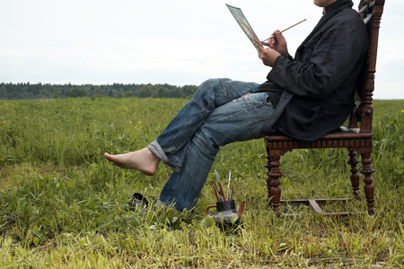 Artist sitting in chair and sketching ideas on a drawing paper. Outdoor cropped shotの写真素材