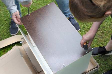 Two people assembling wooden bookshelf outdoor, overhead cropped photoの写真素材