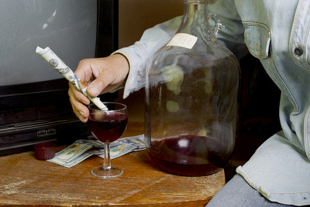 Human hand holding a straw made of a hundred dollar banknote, indoor cropped shotの写真素材