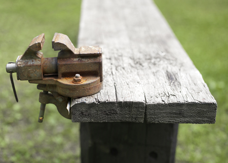 Abandoned rusty clamp attached to a wooden bench. Outdoor cropped shotの写真素材
