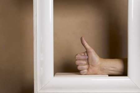 Human hand in painting frame showing okay sign, cropped studio shotの写真素材