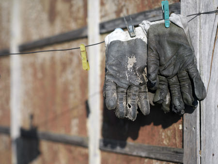 A pair of old leather gloves hanging on a wire, selective color photoの写真素材