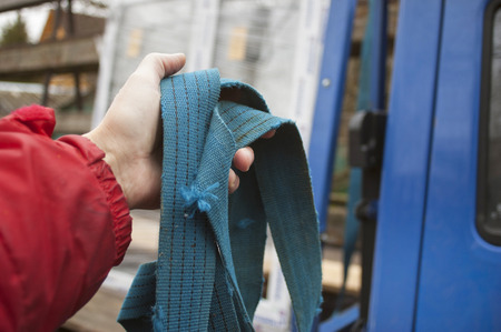 A male hand holding a tow rope and vehicle in the blurred backgroundの写真素材