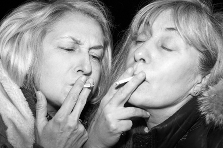 Night scene with two women smoking joints or cigarettes, in black and whiteの写真素材