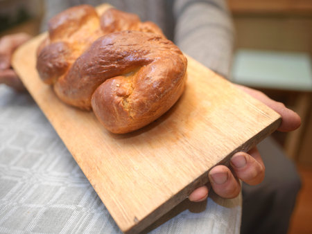 Man sitting at the table and holding a freshly baked bread, selective focus closeupの写真素材
