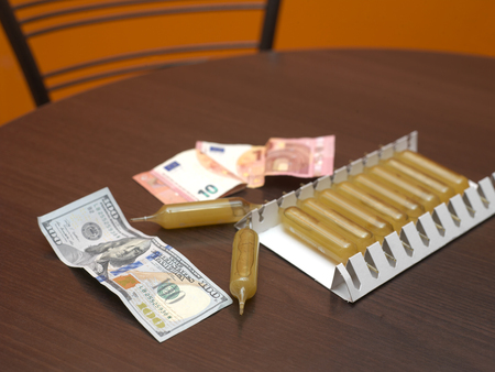 Money and vials spread out on a kitchen table, indoor closeupの写真素材