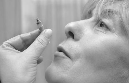 Black and white portraot of a happy looking woman smoking a cigaretteの写真素材