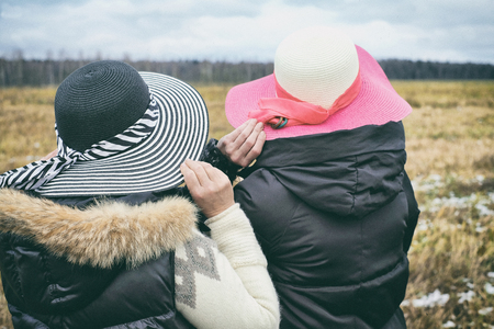 Two female holding their hats in a windy autumn day, outdoor cropped shotの写真素材