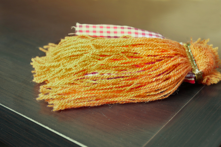 An orange curtain tassel laid on the wooden surface, filtered closeupの写真素材