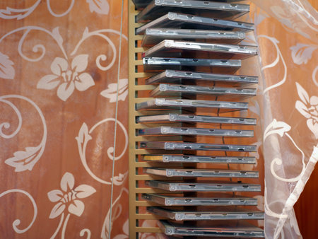 A stand with compact discs next to a silk curtain