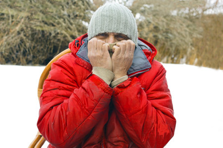 Man wearting winter clothes covering his face with hands, outdoor portrait
