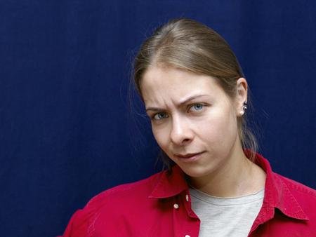 Young female in red shirt with troubled glance, studio shotの写真素材