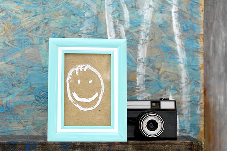 Vintage photo camera and a photo frame with painted smiley face, closeup still lifeの写真素材