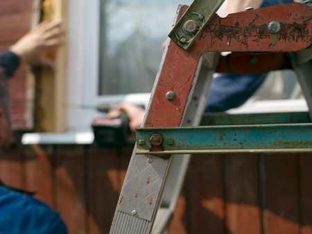 Selective focus shot of the construction ladder and people working in the blurred backgroundの写真素材