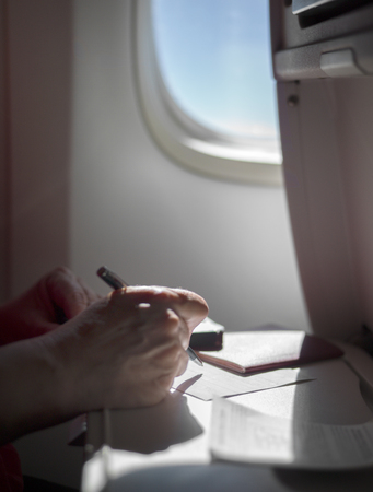 Particular focus shot of a woman filling papers on a board of a planeの写真素材