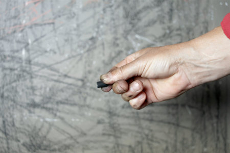 A hand holding charcoal pencil , studio closeup