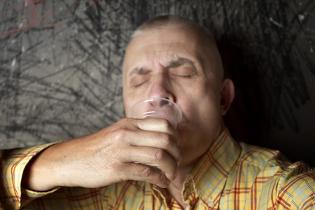 Portrait of a man with shut eyes drinking abstract  beverages in a plastic glassの写真素材