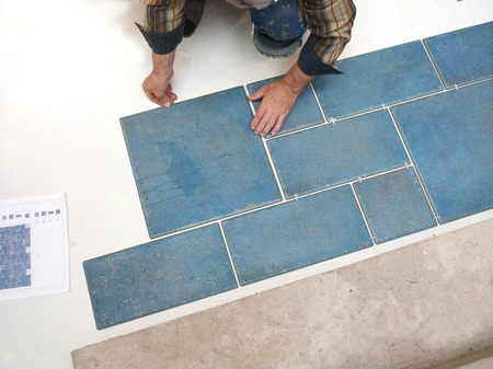 A tiler laying tiles on the floor, overhead cropped shotの写真素材